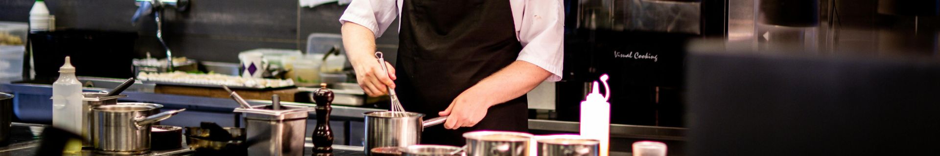 Chef preparing meal in a modern kitchen with various cookware.