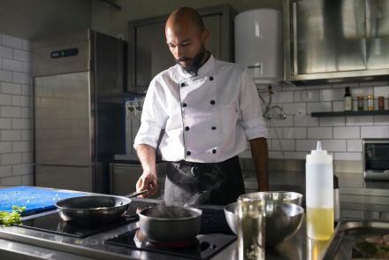 A chef skillfully cooks in a modern kitchen with stainless steel appliances.