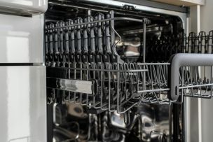 A detailed view of an empty modern dishwasher rack showcasing its stainless steel construction.