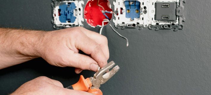 Crop faceless electrician using pliers for installation sockets and switches in new apartment